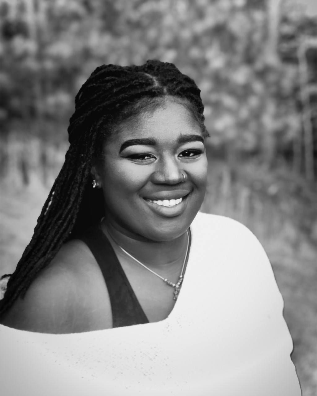 A black and white photo of a woman smiling in a portrait style photo