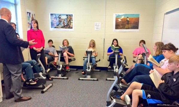 Students reading while on exercise bikes