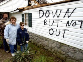 Dyersburg, TN, April 09, 2006 -- A family takes a few minutes from cleaning up their tornado damaged house to stand by their optimistic motto painted on the side of their house. Leif Skoogfors/ FEMA Photo 