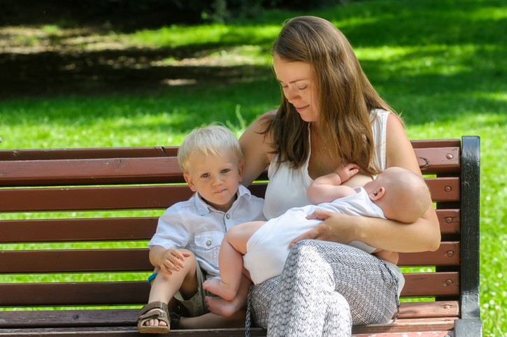 Women breastfeeding infant in park