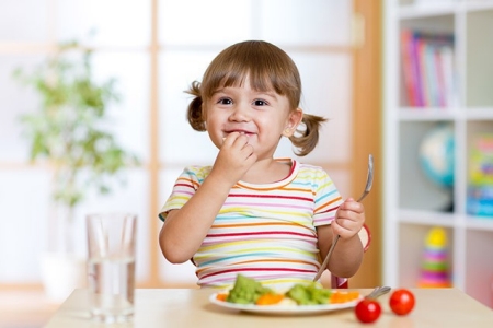 little girl eating vegetables