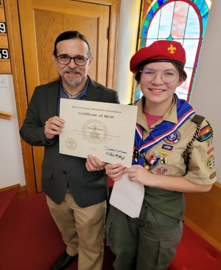 Man presenting THC Merit Award to a woman in a uniform