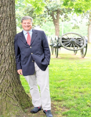 Image of Patrick McIntyre leaning against a tree with a cannon in the background