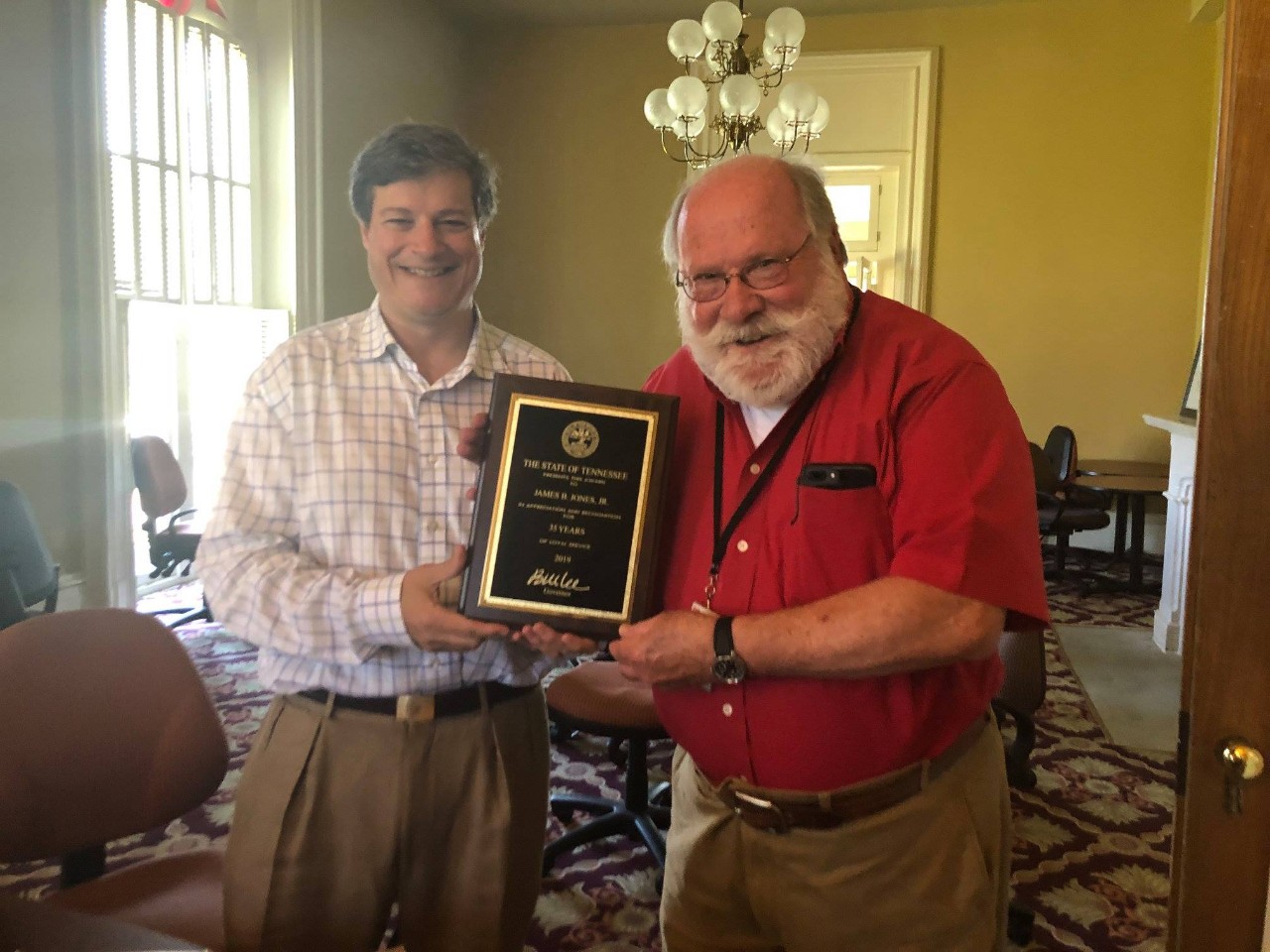 Image of Patrick McIntyre handing a certificate to Jim Jones in a historical home