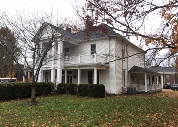 Image of a white Victorian style home with a tree without leaves in front of it.