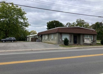 Image of a gray commercial building, parking lot, and a gray SUV car.