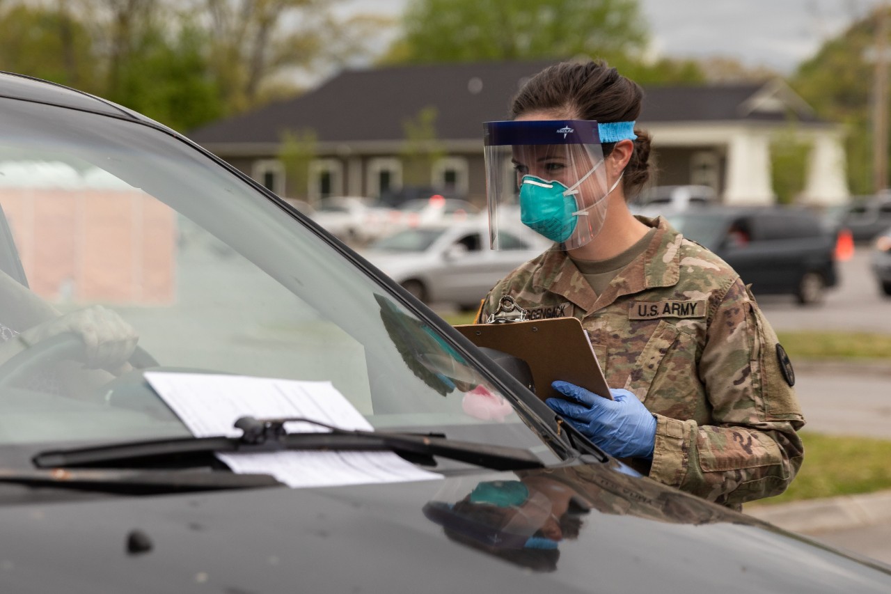Female Tennessee National Guard Soldier in protective gear giving COVID-19 tests at drive-thru facility