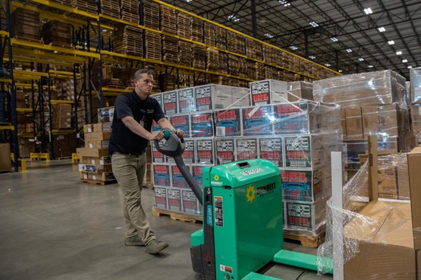 Man moving palettes of supplies in warehouse