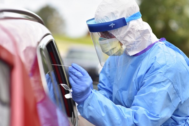 Cpl. Samuel Ross performs a COVID-19 nasal swab at a drive-thru testing site in Cheatham County, Man in protective gear gives a covid-19 test to someone in their car