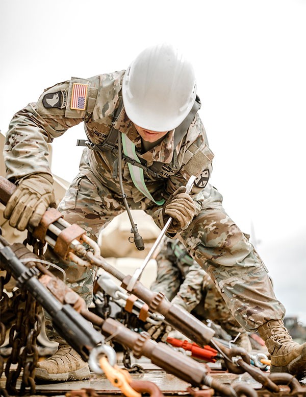 A Soldier from the 230th Sustainment Brigade chains down an M3 Bradley Fighting Vehicle during railhead operations at Fort Hood, Texas, as they support the 278th Armored Cavalry Regiment conducting an eXportable Combat Training Capability exercise throughout the month of July. (Photo by Pfc. Everett Babbitt)