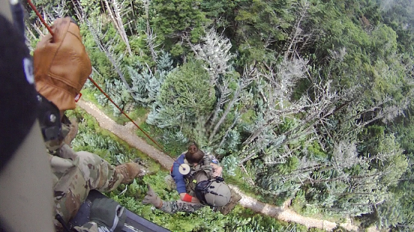 Sgt. 1st Class Tracy Banta, a Tennessee National Guard Flight Paramedic, is hoisted into a rescue helicopter with a hiker who has life-threatening illness on Mount LeConte at the Great Smoky Mountain National Park area, July 19. (Photo from the Tennessee National Guard)
