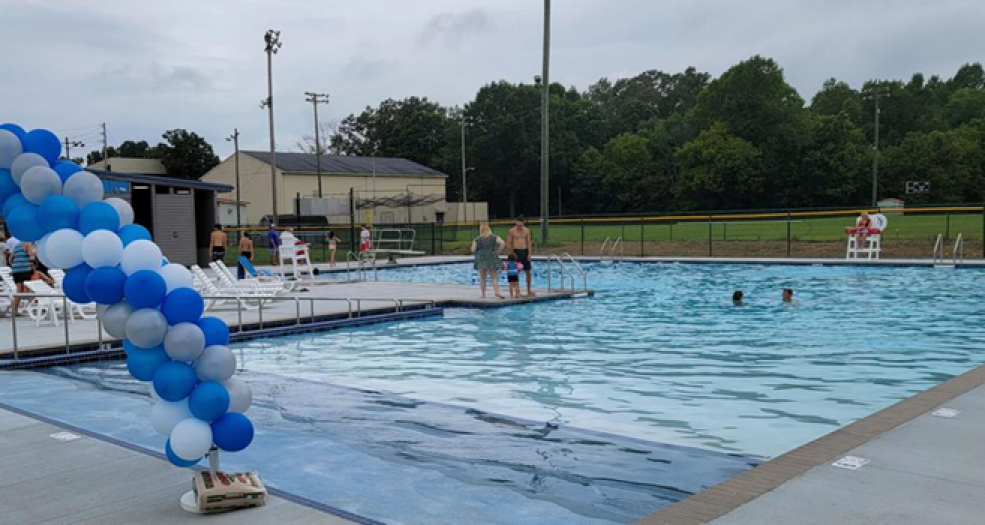 An outdoor swimming pool is filled with water and surrounded by a deck and seating.