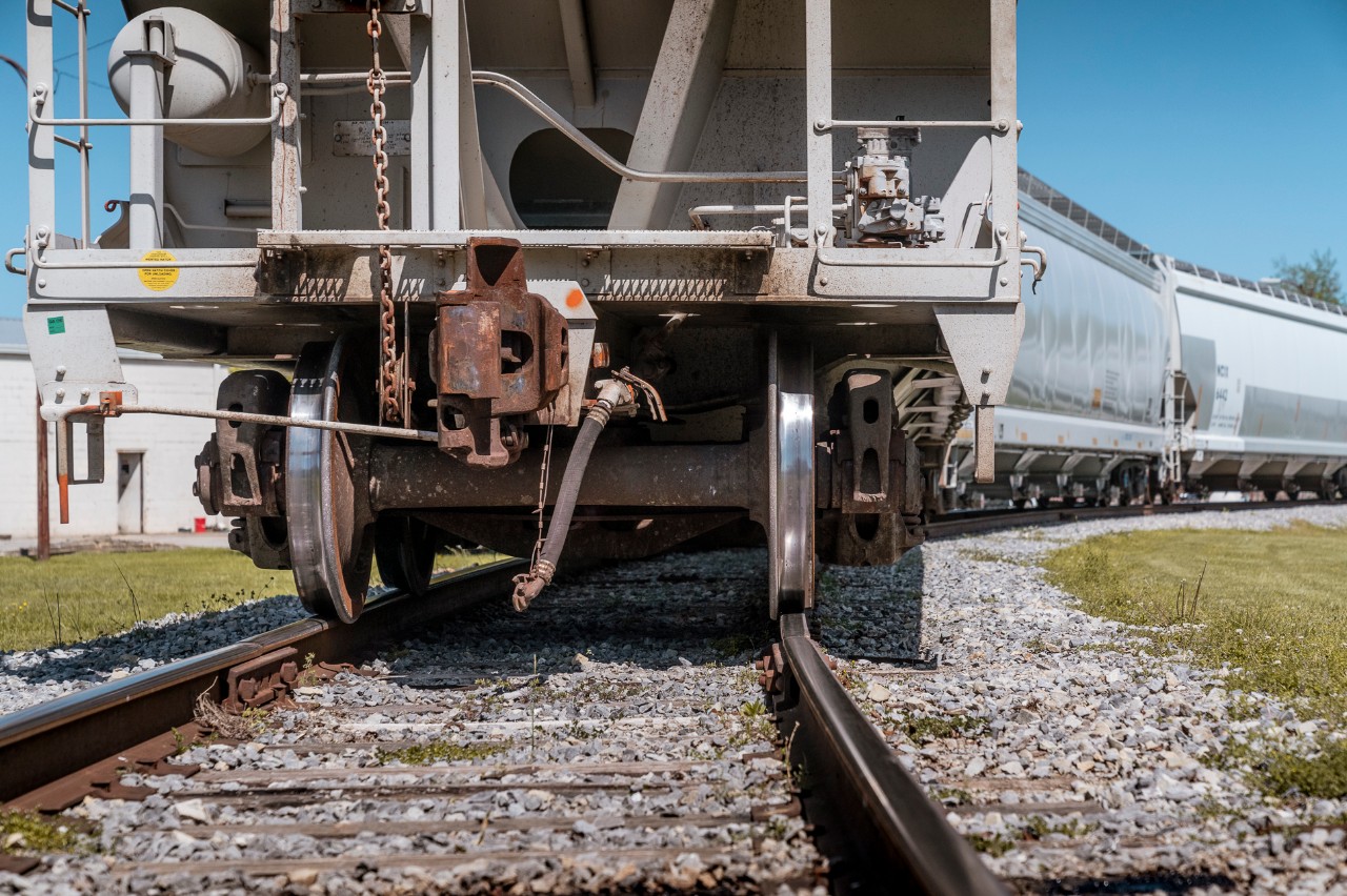 Close-up of a freight railcar’s wheels and coupler on railroad tracks.