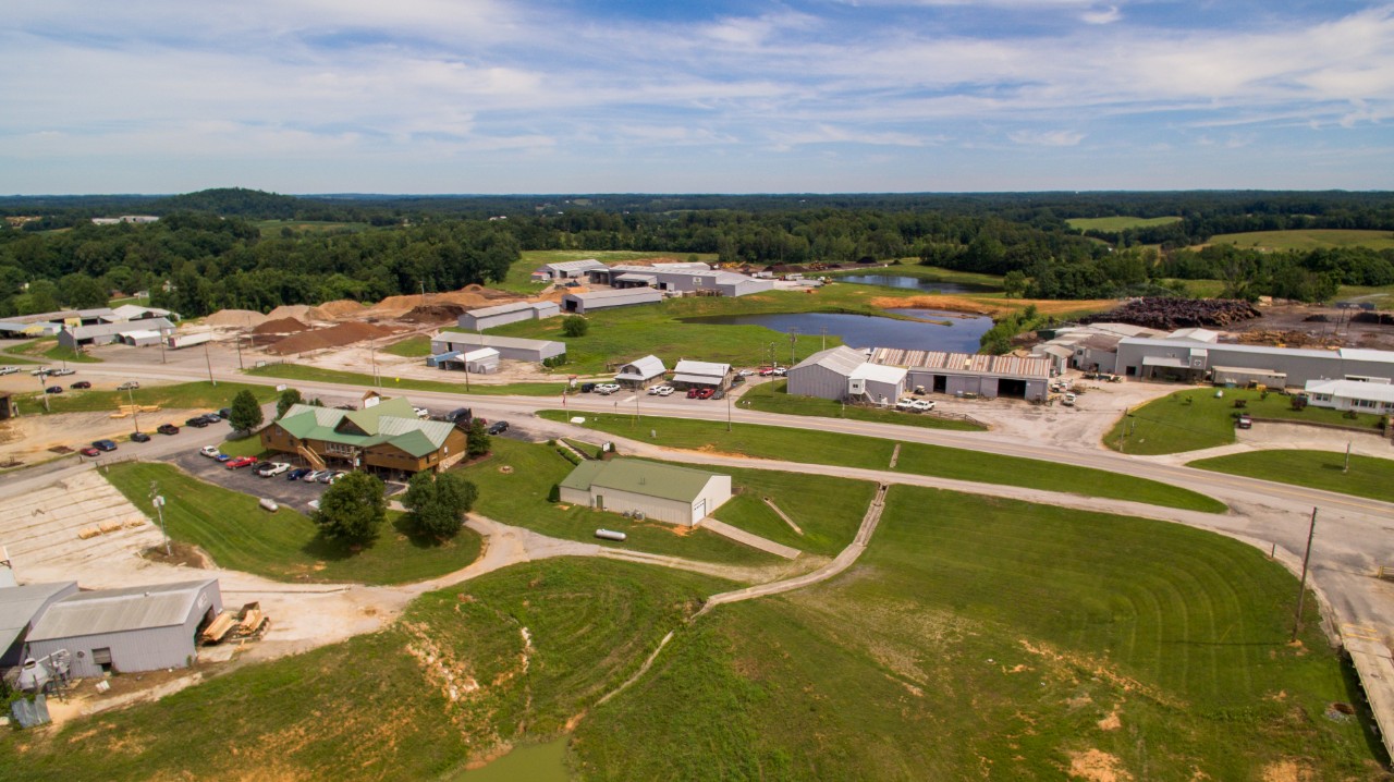 Aerial view of an industrial and commercial area with warehouses, office buildings, ponds, and surrounding farmland.