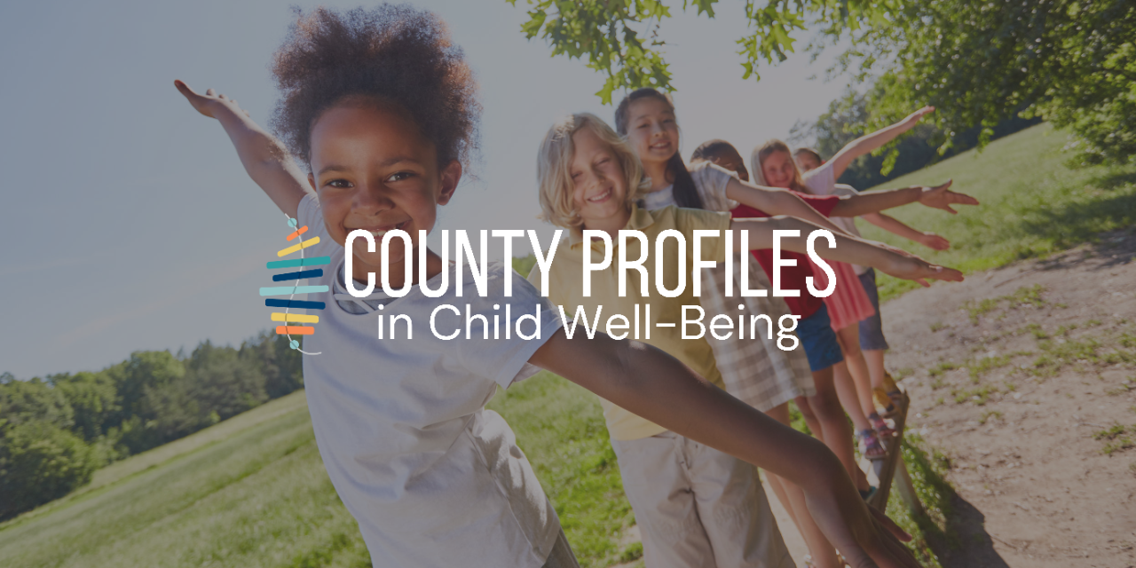 Diverse children balancing in line on a log, smiling at camera. 