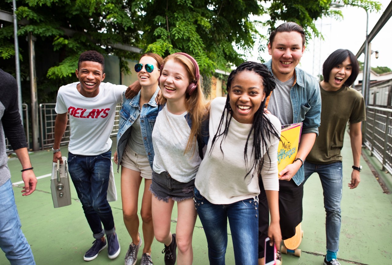 Image shows diverse group of teens, smiling and looking at the camera 