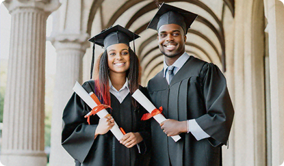 Photo of two students in graduation caps and gowns with diplomas