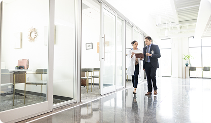 Photo of two people in business clothes walking through a modern office hallway