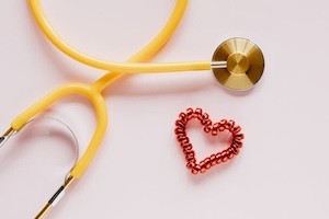 A yellow stethoscope with a heart shape next to it