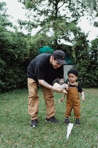 Father and son playing outside with a paper airplane