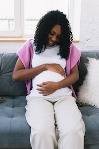 Prenatal Health Care A pregnant woman smiling and looking at her belly