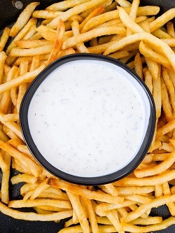 greek yogurt ranch dressing in a circular container, fries surround the container