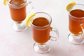 three non-alcoholic hot not-toddy drinks in clear glasses on a table with lemon garnishes