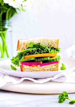 A sandwich with fresh veggies on a plate