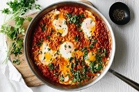 overhead view of shakshuka in a pan sitting on a cutting board