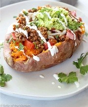 a sweet potato with taco meat, guacamole, salsa and sour cream