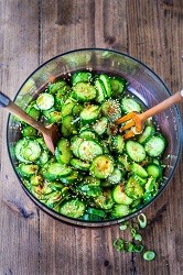 a large bowl of cucumber salad with a wooden spoon and fork