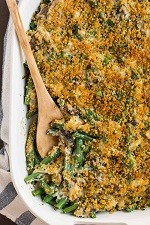 a casserole dish of green bean casserole with a wooden spoon in it
