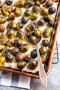 roasted Brussels sprouts on a baking sheet with a spoon