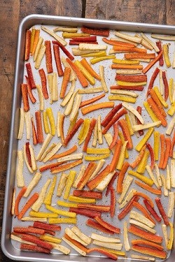 sliced roasted carrots and parsnips on a baking sheet