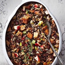 wild rice stuffing with apple and sausage in a large dish with a serving spoon