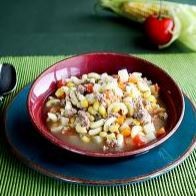 beef and vegetable soup in a bowl with a plate under the bowl