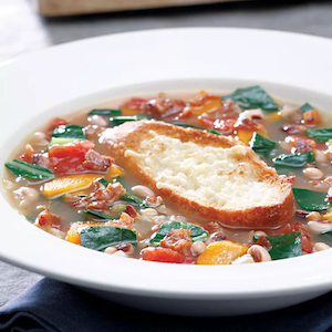 collard green and black eyed pea soup with bread in the center