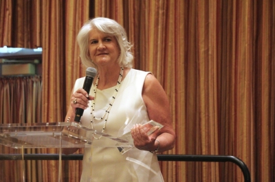 Kitty Boyte on stage holding the Sue Ann Head Award trophy