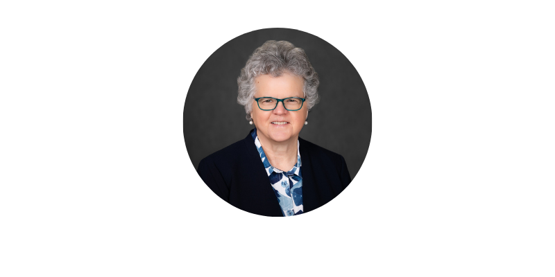 Aging Conference Headshots - Kathy Greenlee Woman with glasses on smiling in front of a gray background.
