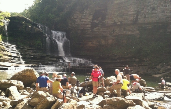 Several people gathered at the base of a waterfall on Blackburn Fork Scenic River.