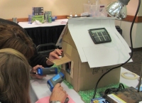 People working on a miniature energy efficient house People working on a miniature energy efficient house