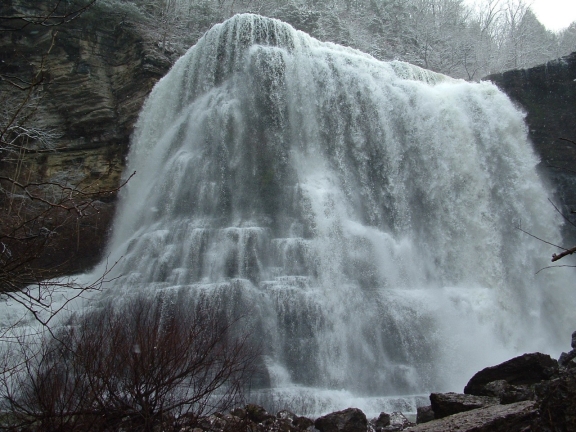 A large waterfall pours over a rock face in winter at Burgess Fall