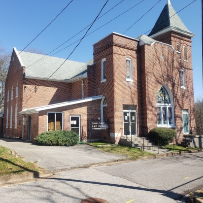 Quinn Chapel A.M.E. Church Quinn Chapel A.M.E. Church, a large brick church with a steeple. It is accessed by concrete steps. A parking lot and paved road is visible in the foreground.