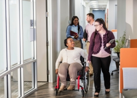 A women in a wheelchair travels alongside her friend as they're on their way to class. A women in a wheelchair travels alongside her friend as they're on their way to class.