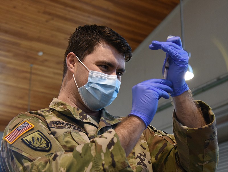 Sgt. Dillon Henderson with Smyrna’s 208th Medical Company prepares to administer the Moderna vaccine at Smyrna’s Volunteer Training Site on Jan. 28. (photo by Sgt. 1st Class Edgar Castro) Soldier using a syringe with doses of the COVID-19 vaccine