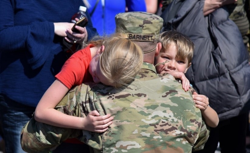 A Soldier deploying with the Tennessee National Guard’s 1st Battalion, 181st Field Artillery Regiment, hugs his family goodbye as he departs Smyrna’s Volunteer Training Site for a 10-month deployment to the Middle East on March 7. (photo by Staff Sgt. Timothy Cordeiro) Soldier hugging his children