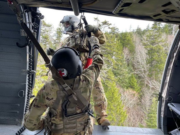 Spc. Joshua Culotta begins hoist operations and lowers Sgt. 1st Class Giovanni DeZuani to a patient at the Tri Corner Knob Shelter on the Appalachian Trail, May 9. (Courtesy photo from the Tennessee National Guard) Soldier in a helicopter preparing to lower another Soldier down to help a hiker