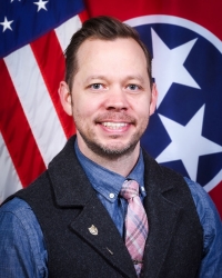 Photo of Matthew Thompson in tie and dress attire in front of the United States Flag and State of Tennessee Flag. Photo of Matthew Thompson in tie and dress attire in front of the United States Flag and State of Tennessee Flag.