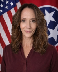 Photo of Ali Wilhelm in tie and dress attire in front of the United States Flag and State of Tennessee Flag. Photo of Ali Wilhelm in tie and dress attire in front of the United States Flag and State of Tennessee Flag.