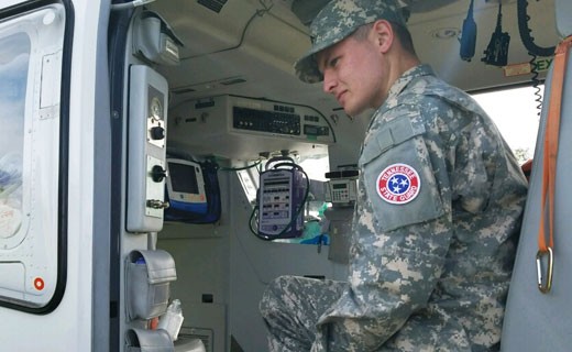 A Tennessee State Guard Soldier in uniform sitting in a vehicle surrounded by equipment. A Tennessee State Guard Soldier in uniform sitting in a vehicle surrounded by equipment.